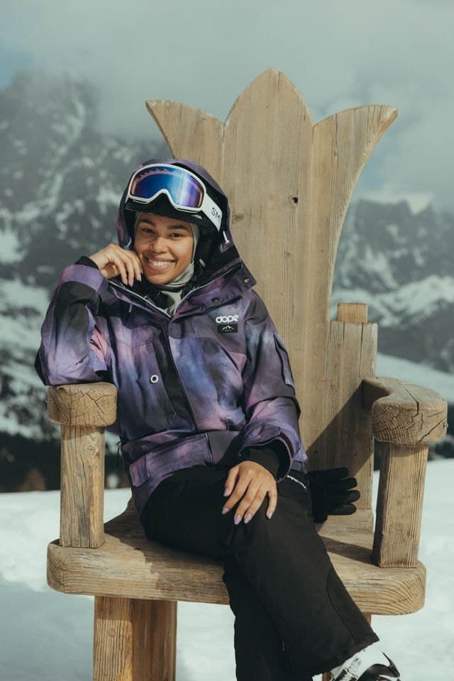 A traveler smiling on a carved wooden throne in the snow