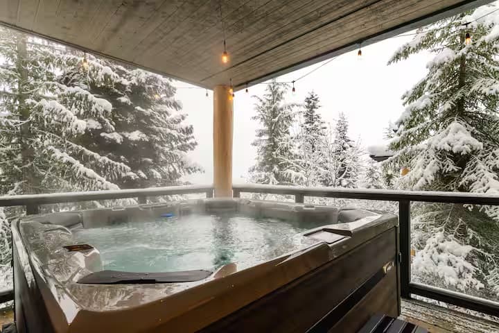 Private hot tub on the covered deck surrounded by snowy trees